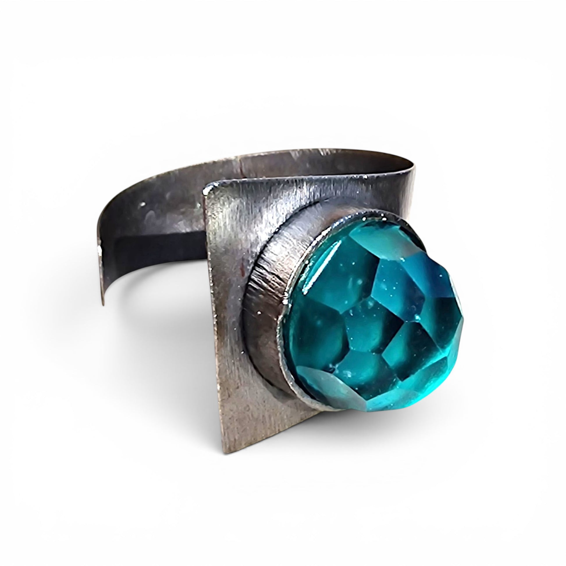 Selce bracelet angled view — square iron cuff with sea-green faceted Murano glass stone