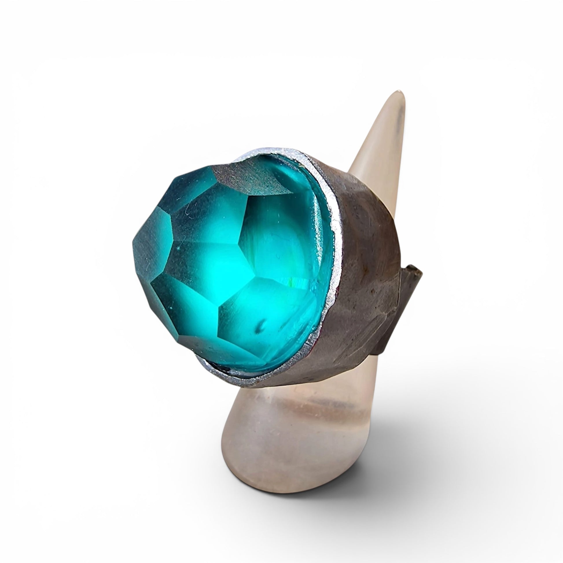 Selce Murano glass ring on display stand — faceted teal Murano glass set in handcrafted wrought iron, white background